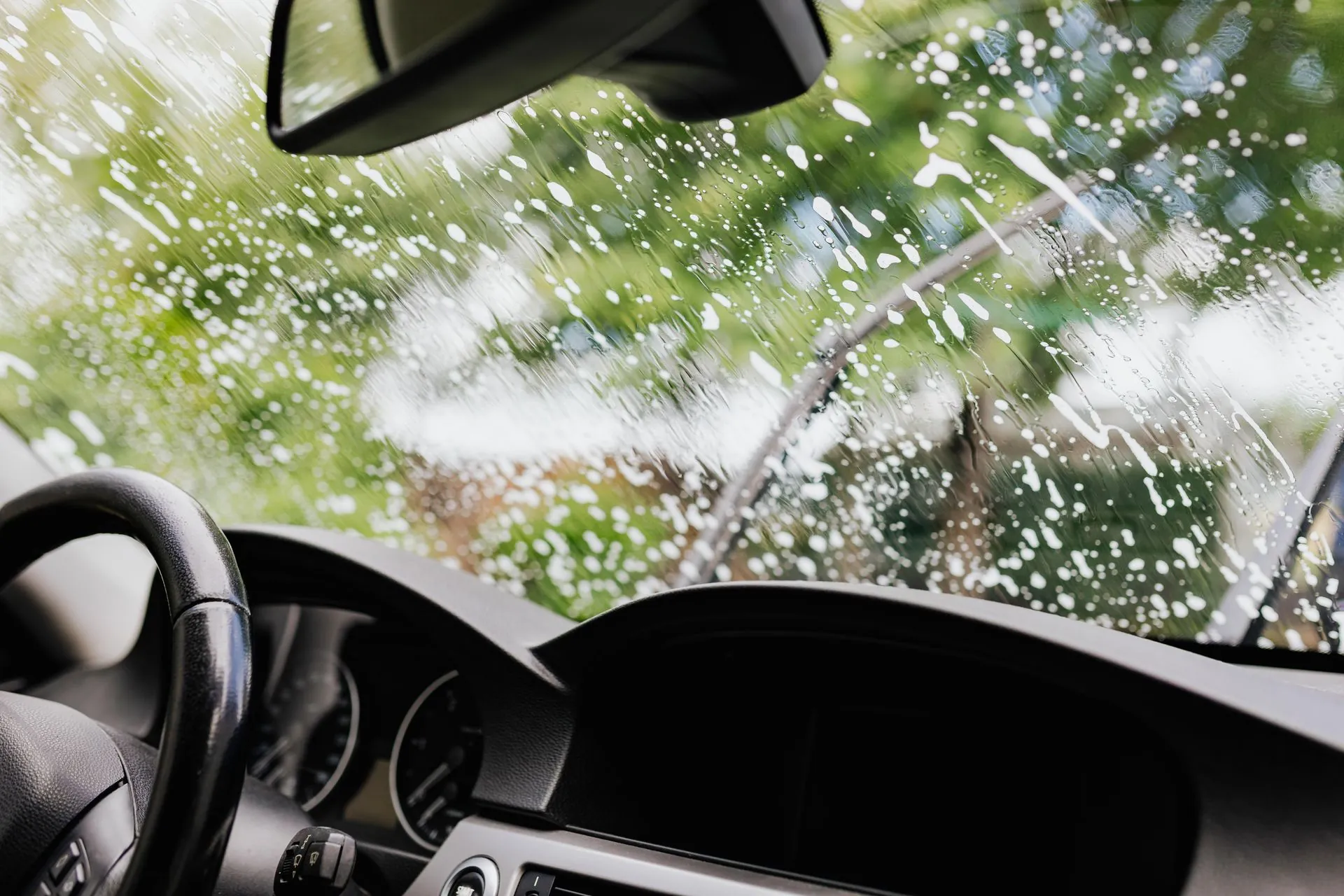 The view out through a windscreen from the driver's seat as water sprays across the glass.